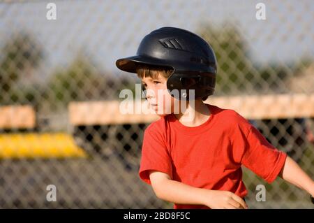 Young boy in baseball helmet concentrating on his hit Stock Photo