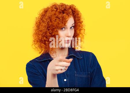 It's you! portrait of a beautiful woman redhead curly 80's retro style pointing at you camera happy isolated yellow background wall. Body language, ge Stock Photo