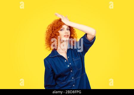Regrets wrong doing. Closeup portrait silly young redhead curly woman slapping hand on head having duh moment isolated yellow background Negative huma Stock Photo