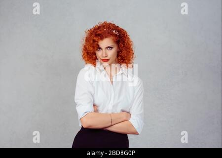 Grumpy girl. Closeup portrait young serious angry redhead curly ginger hair woman isolated on gray wall background. Negative human emotion feelings fa Stock Photo