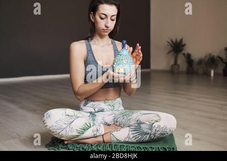 young woman meditates alone in yoga studio with aroma lamp Stock Photo