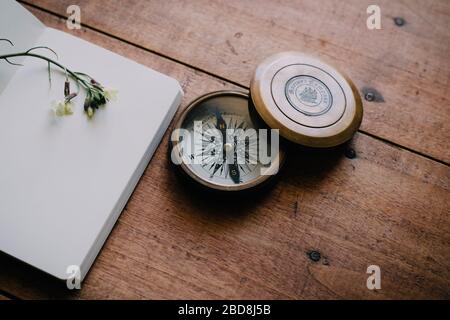 Old compass on wooden table next to notebook Stock Photo