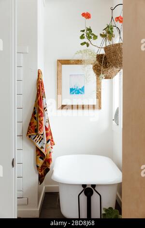 hanging flower, Pendleton towel, and a claw foot tub in white bathroom Stock Photo
