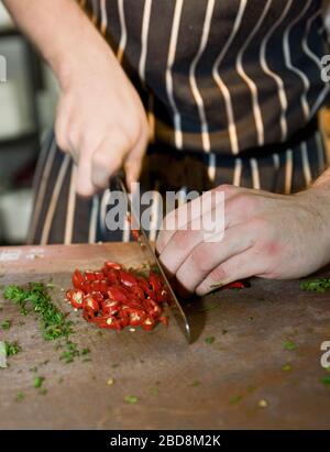 close up of chef chopping red chili peppers at commercial kitchen Stock Photo