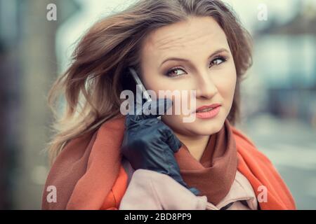 Skeptical woman talking on mobile phone. Closeup portrait upset unhappy serious business woman displeased with conversation isolated on city urban bac Stock Photo