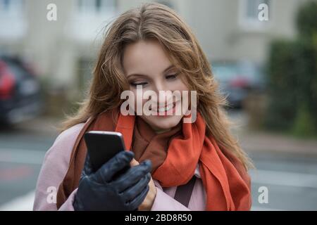 Woman texting. Closeup young happy smiling cheerful beautiful businesswoman looking mobile cell phone reading sending sms isolated cityscape outdoor b Stock Photo