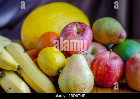 A still life shot with an assortment of different types of fruit including apples, mandarin oranges, melon, banana, pears, mango, lemon Stock Photo