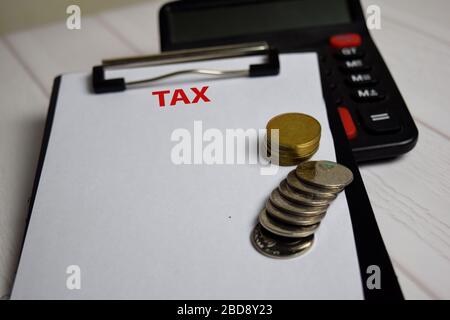 Tax write on paperwork on clipboard and the stack of coint. Finance or Tax Concept Stock Photo