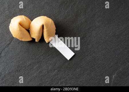 View of fortune cookies from above with a blank fortune on a black slate background with copy space; landscape view Stock Photo