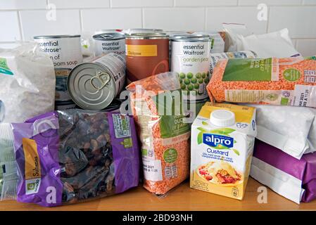 Tins and packets of dried food piled up on kitchen work surface after home delivery.  Stockpiling due to Coronavirus Corvid 19 pandemic lockdown. Stock Photo