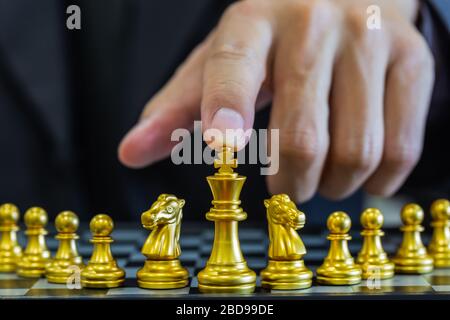 Chess game on chess board behind business man background. Business concept to present financial information and marketing strategy analysis. Investmen Stock Photo
