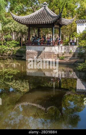 Suzhou China - May 3, 2010: Humble Administrators Garden. Pavilion in traditional architecture is reflected greenish water of canal. Green foliage as Stock Photo