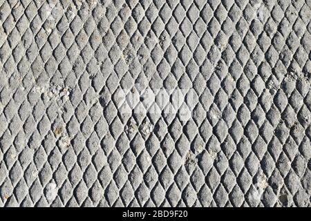 Weathered and aged sidewalk concrete with a diamond patterned texture. Stock Photo