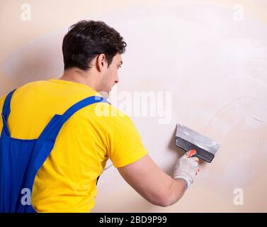 The young contractor employee applying plaster on wall Stock Photo