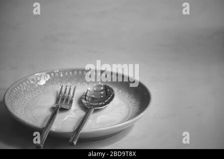 Empty plate at a closed restaurant shows the loneliness, economic crisis, hunger and depression as a result of social distancing, lock down and self i Stock Photo