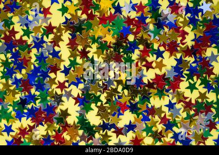 Colorful star shaped sparkles on yellow as the best background for your creative design. Festive concept Stock Photo