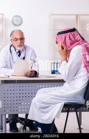 The young male arab visiting experienced male doctor Stock Photo
