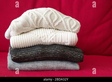 Closeup shot of warm sweaters on red sofa in living room Stock Photo