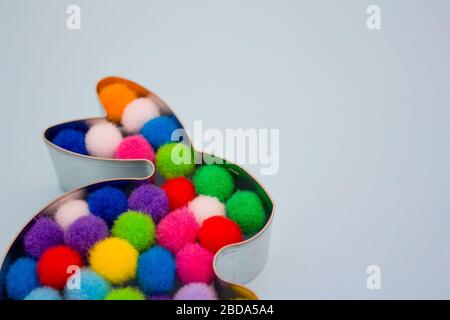 Close up of rabbit bunny shaped form for gingerbread decorated with colorful balls inside on light grey background with copy space. Easter concept Stock Photo