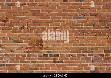 Antique red and brown exterior clay brick wall texture background, with rugged deterioration, photographed in sunlight, Stock Photo
