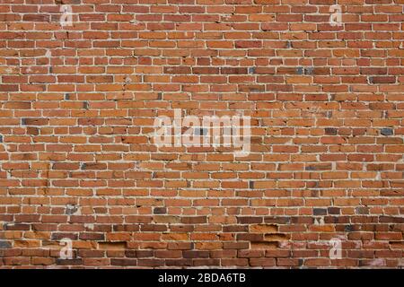 Antique red and brown exterior clay brick wall texture background, with rugged deterioration, photographed in sunlight, Stock Photo