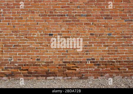 Antique red and brown exterior clay brick wall texture background, with rugged deterioration, photographed in sunlight, Stock Photo