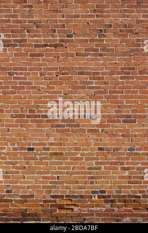 Antique red and brown exterior clay brick wall texture background, with rugged deterioration, photographed in sunlight, Stock Photo