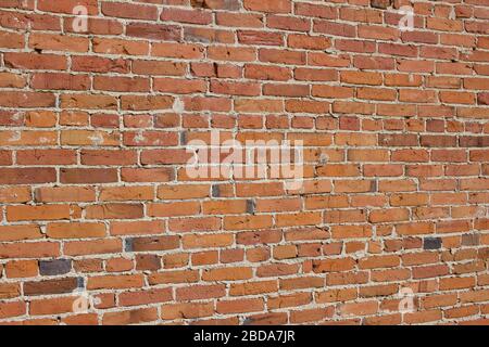 Antique red and brown exterior clay brick wall texture background, with rugged deterioration, photographed in sunlight, Stock Photo