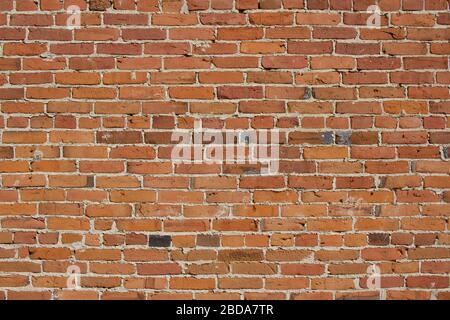 Antique red and brown exterior clay brick wall texture background, with rugged deterioration, photographed in sunlight, Stock Photo
