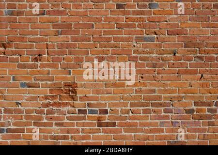 Antique red and brown exterior clay brick wall texture background, with rugged deterioration, photographed in sunlight, Stock Photo