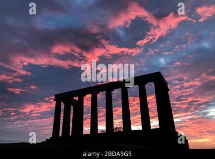 The sun rises behind the National Monument of Scotland on Calton Hill, Edinburgh.