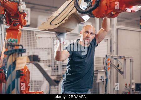 Engineer setting up automatic robot arm for production in automotive, industry factory, industrial concept Stock Photo