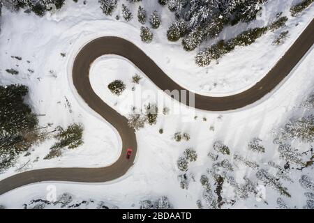 Car traveling on snowy winding road connecting Antorno and Misurina from above, Dolomites, Belluno province, Veneto, Italy Stock Photo