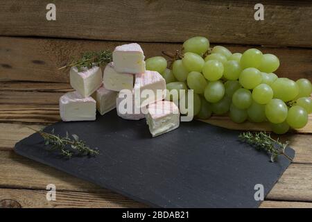 Frnch white mold  cheeses grapes walnuts and a cheese knife on the stone background Stock Photo