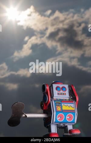 Vintage toy robot with sky behind. Artificial intelligence concept. Dark ambient. Stock Photo