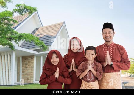 portrait of asian family muslim with traditional greeting gesture in front of the house Stock Photo