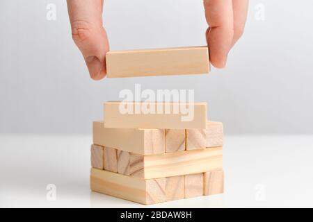A hand holds two wooden blocks with bold blue letters forming the words