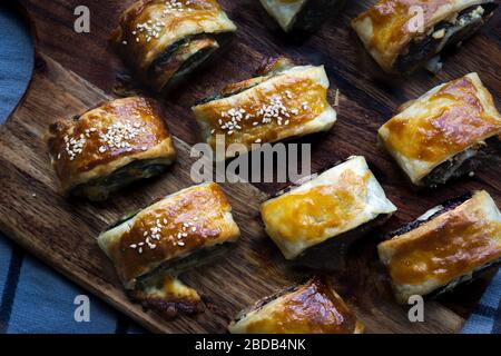 Home made vegan sausage rolls with cheese and spinach pastry topped with sesame seeds. Stock Photo