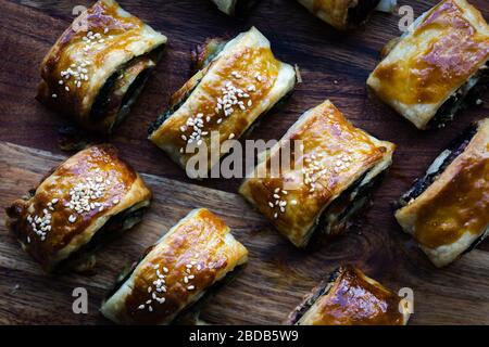 Home made vegan sausage rolls with cheese and spinach pastry topped with sesame seeds. Stock Photo