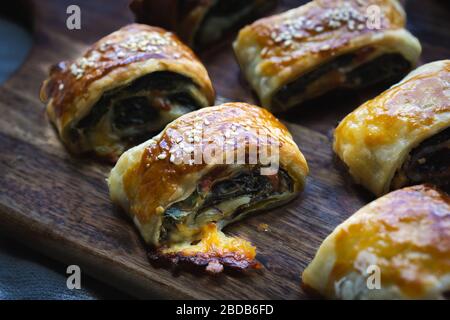 Home made vegan sausage rolls with cheese and spinach pastry topped with sesame seeds. Stock Photo