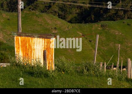 Rusty corrugated iron shed in hilly farmland, Glenburn, Wairarapa, New Zealand Stock Photo