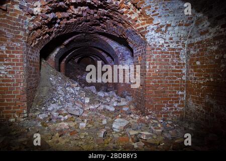 Old collapsed ruined underground red brick historical vaulted tunnel Stock Photo