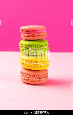 Multi-colored macaroons stand in a pile on a pink table Stock Photo
