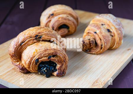 composition, three croissants with chocolate filling on a wooden table Stock Photo