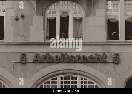 Illuminated lettering on a house wall, translated into English: labor law, labor law neon sign, Arbeitsrecht, black and white Stock Photo
