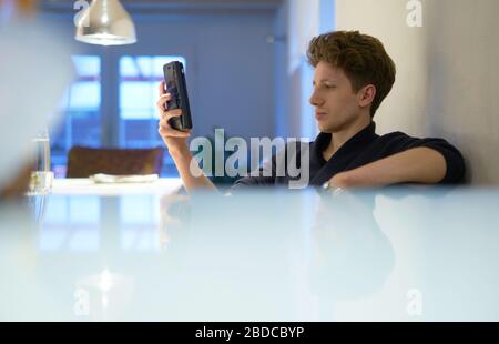 portrait of young handsome man sitting in his apartment and holding a cell phone in his hand Stock Photo