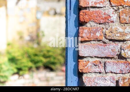 Background from a fragment of a wall with a blue frame. Red brick. Blue board. Blurry background. Stock Photo