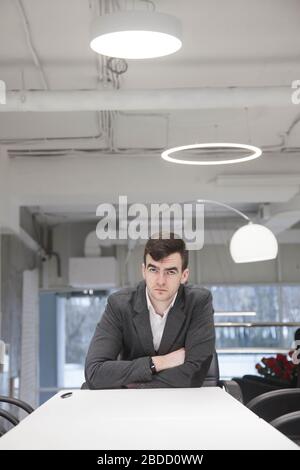 A young businessman works with documents at a white table in a modern interior Stock Photo