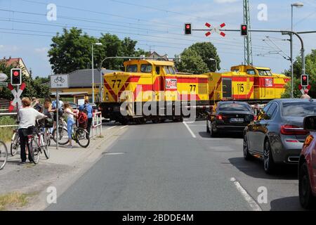 12.06.2018, Luebben, Brandenburg, Germany - Cars and cyclists wait at a railroad crossing for a train to pass through. 00S180612D399CAROEX.JPG [MODEL Stock Photo