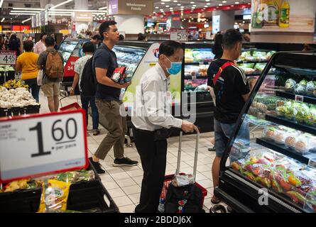 25.03.2020, Singapore, , Singapore - An elderly man is wearing a respirator mask when shopping in a supermarket in the Ang Mo Kio district to protect Stock Photo